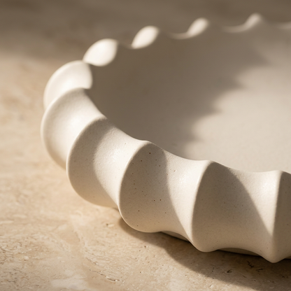 Close-up of the sculptural fluted rim of an ivory ceramic tray